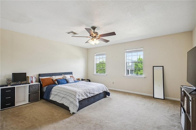 carpeted bedroom with a textured ceiling, visible vents, ceiling fan, and baseboards