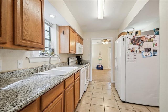 kitchen with a sink, light tile patterned floors, brown cabinetry, a ceiling fan, and white appliances