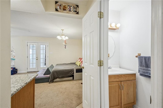 bedroom featuring access to exterior, an inviting chandelier, french doors, and light colored carpet
