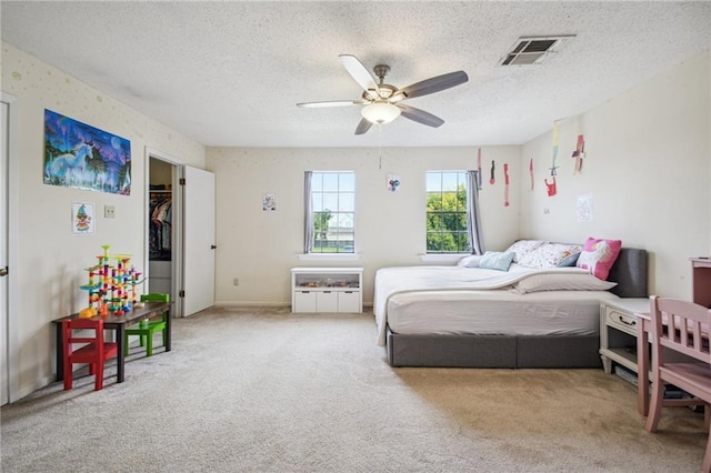 carpeted bedroom with a textured ceiling, visible vents, and ceiling fan