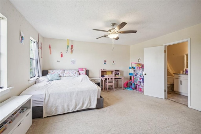 bedroom featuring ensuite bathroom, ceiling fan, a textured ceiling, and light colored carpet