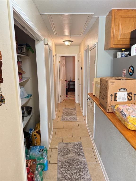 4928 Sandalwood St, New Orleans, LA 70127 - hallway with attic access, light tile patterned flooring, and baseboards