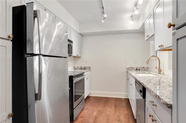 1430 Jackson Ave Unit 302, New Orleans, LA 70130 - kitchen with appliances with stainless steel finishes, wood finished floors, light stone counters, white cabinetry, and track lighting
