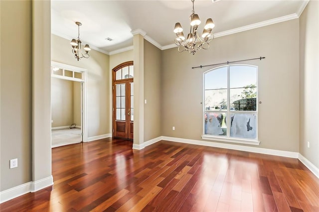 spare room with wood finished floors, a chandelier, and crown molding