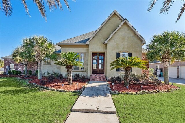 318 Cape Breton Dr, Slidell, LA 70458 - view of front of house featuring stucco siding, french doors, a front yard, and a shingled roof