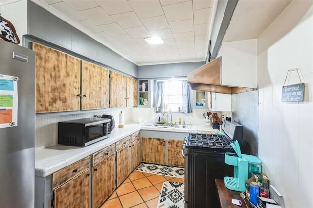 119 Vine St, New Iberia, LA 70560 - kitchen featuring stainless steel gas range oven, fridge, tile counters, and decorative backsplash