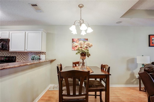 1700 Marseille Dr Unit 2, La Place, LA 70068 - dining room featuring visible vents, baseboards, light wood-style flooring, an inviting chandelier, and a textured ceiling