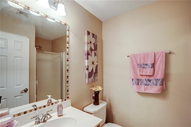 1700 Marseille Dr Unit 2, La Place, LA 70068 - bathroom with visible vents, toilet, a textured ceiling, a shower stall, and vanity