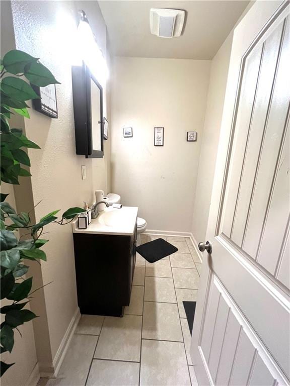 bathroom featuring tile patterned flooring, toilet, vanity, and baseboards