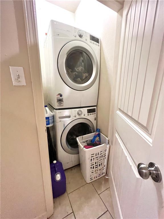laundry area with light tile patterned floors, laundry area, and stacked washer / dryer