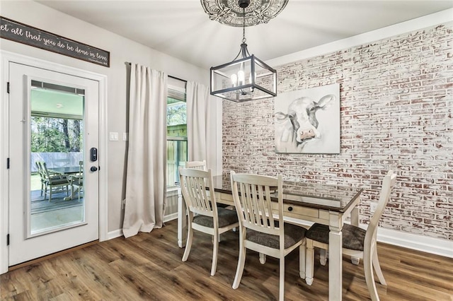 41379 Schafer Dr, Hammond, LA 70403 - dining area featuring a chandelier, plenty of natural light, brick wall, and wood finished floors