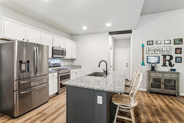 41379 Schafer Dr, Hammond, LA 70403 - kitchen with appliances with stainless steel finishes, wood finished floors, white cabinets, recessed lighting, and a breakfast bar