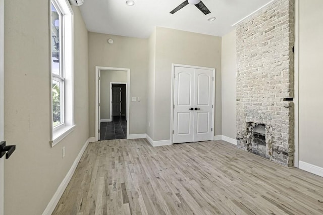 unfurnished living room featuring a fireplace, wood finished floors, baseboards, and ceiling fan