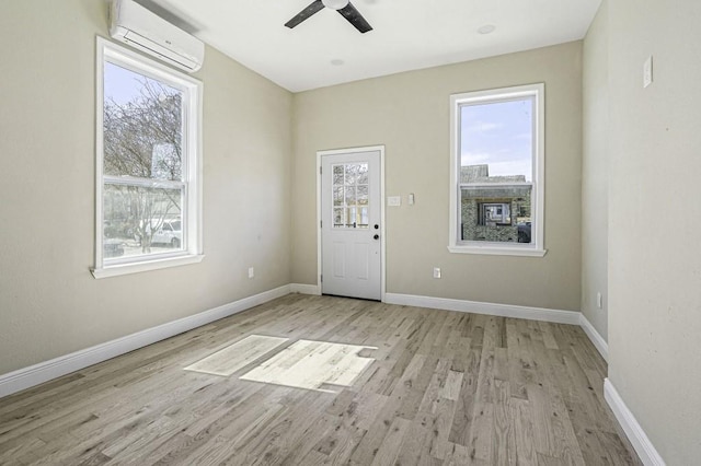 foyer featuring light wood-type flooring, baseboards, an AC wall unit, and ceiling fan