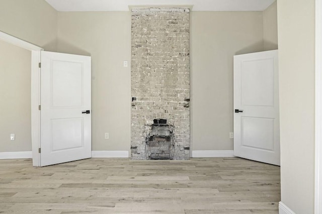 unfurnished living room with a fireplace, wood finished floors, and baseboards