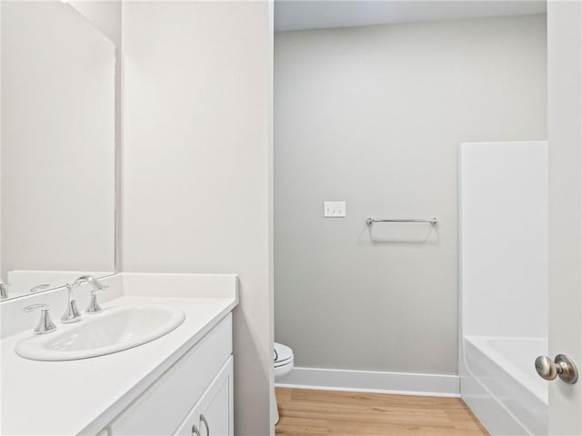 72694 Robindale Dr, Covington, LA 70435 - bathroom featuring a tub to relax in, vanity, toilet, wood finished floors, and baseboards