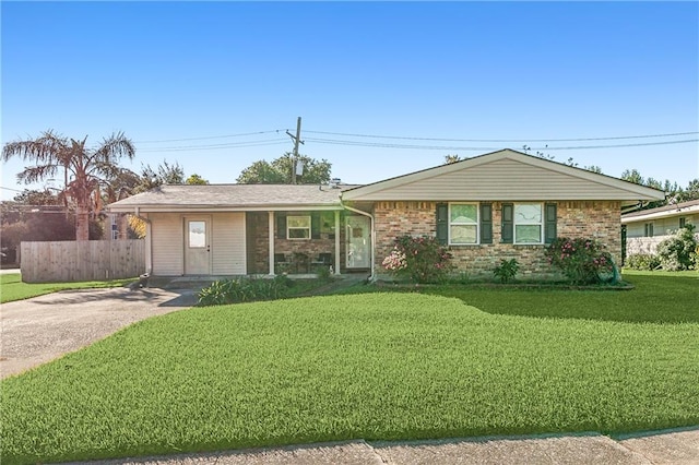 ranch-style house with brick siding, driveway, a front yard, and fence