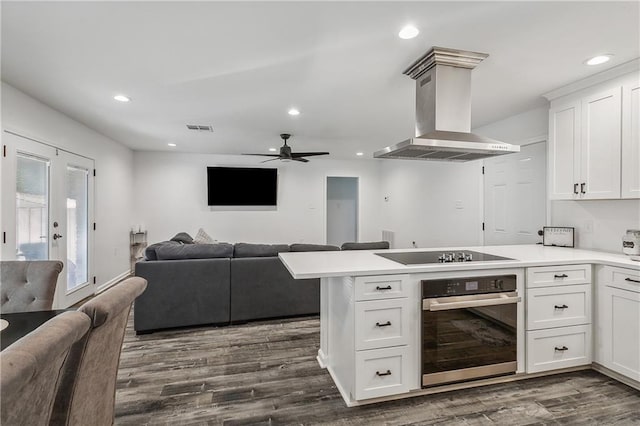 kitchen with oven, visible vents, a peninsula, wall chimney range hood, and black electric cooktop