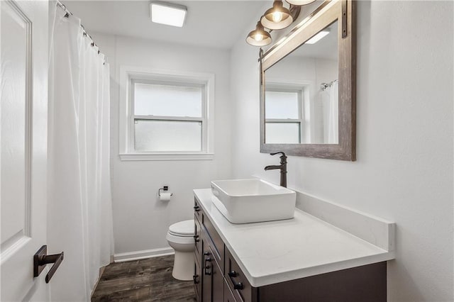 bathroom with plenty of natural light, toilet, vanity, and wood finished floors