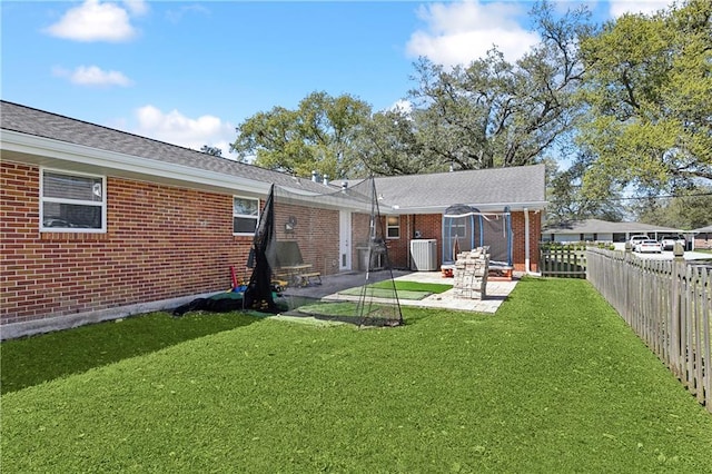 back of house featuring central air condition unit, a lawn, a fenced backyard, and brick siding
