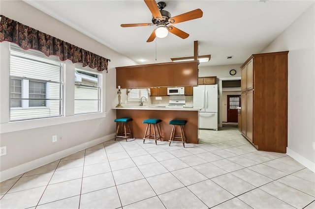 1534 General Collins Ave, New Orleans, LA 70114 - kitchen with white appliances, a peninsula, ceiling fan, a sink, and a kitchen bar