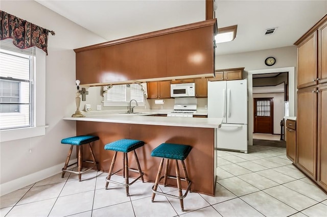 1534 General Collins Ave, New Orleans, LA 70114 - kitchen featuring white appliances, visible vents, a peninsula, a kitchen bar, and brown cabinets