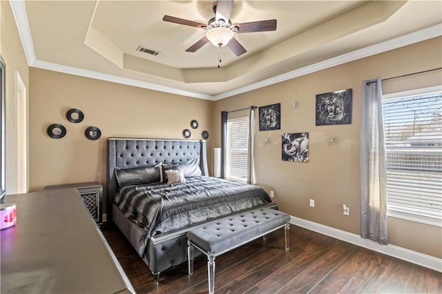 bedroom with visible vents, a ceiling fan, a tray ceiling, wood finished floors, and baseboards