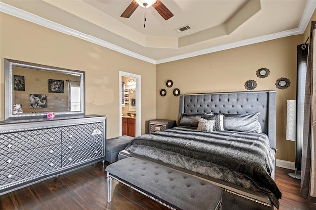 bedroom with visible vents, ornamental molding, ensuite bathroom, wood finished floors, and a raised ceiling