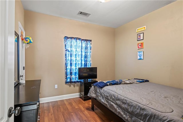 bedroom with visible vents, baseboards, and wood finished floors