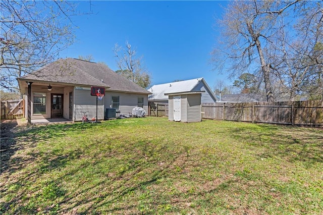 view of yard with a patio area, central AC unit, a storage shed, a fenced backyard, and an outbuilding