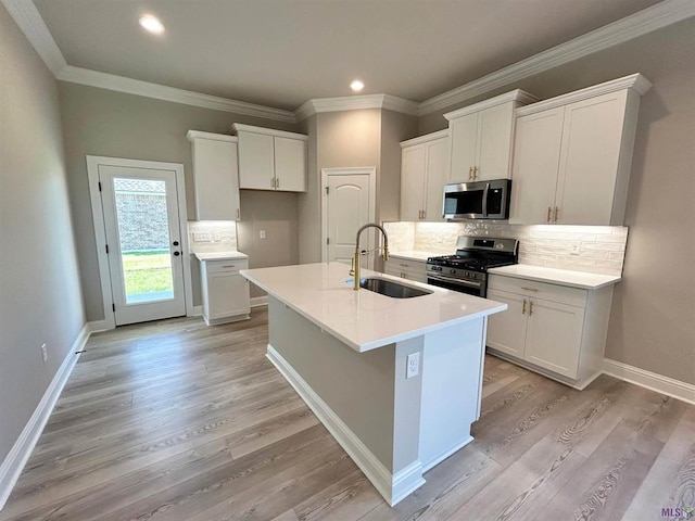 25307 Angele Dr, Ponchatoula, LA 70454 - kitchen featuring stainless steel appliances, a center island with sink, decorative backsplash, white cabinetry, and ornamental molding