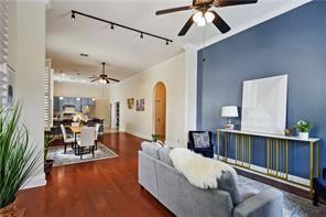 living room with wood finished floors, a ceiling fan, arched walkways, and track lighting