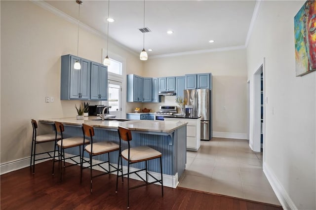 kitchen with visible vents, blue cabinetry, appliances with stainless steel finishes, a peninsula, and a sink