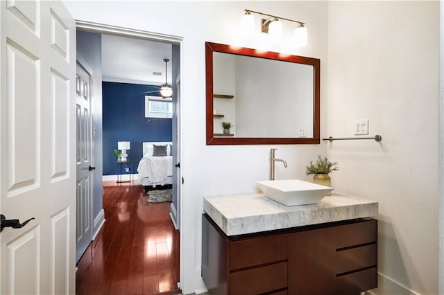 bathroom with hardwood / wood-style floors, vanity, baseboards, visible vents, and ceiling fan