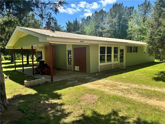 back of house featuring a yard, metal roof, and an attached carport