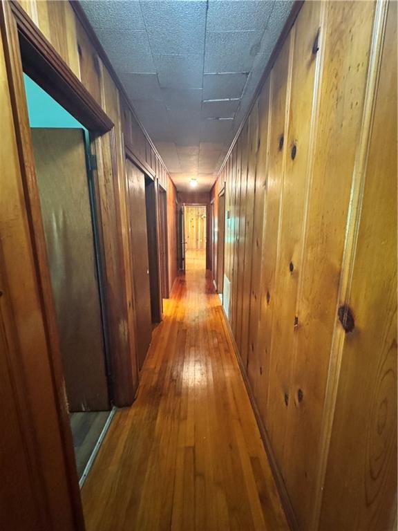 hallway with wood walls and light wood-style flooring