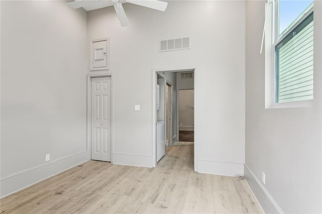 unfurnished bedroom with baseboards, a high ceiling, wood finished floors, and visible vents