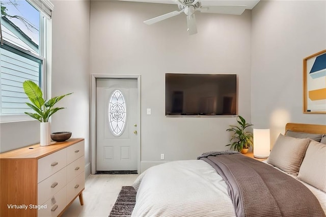 bedroom featuring a high ceiling and light wood-type flooring