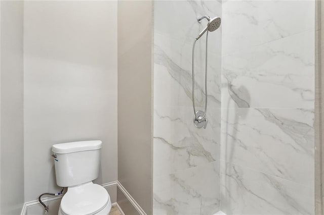 bathroom featuring baseboards, a marble finish shower, and toilet