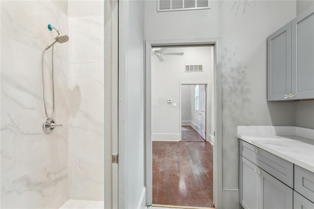 full bath with visible vents, a marble finish shower, hardwood / wood-style flooring, and vanity
