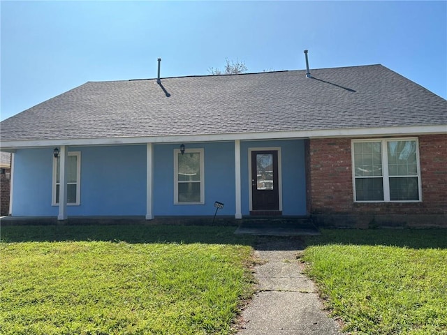 single story home featuring a front yard, brick siding, and roof with shingles