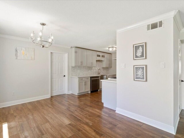 1840 Carol Sue Ave, Terrytown, LA 70056 - kitchen with dark wood-style floors, ornamental molding, light countertops, dishwasher, and a notable chandelier
