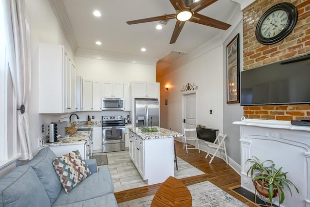 326 N Tonti St, New Orleans, LA 70119 - kitchen with appliances with stainless steel finishes, ornamental molding, a center island, ceiling fan, and light stone counters
