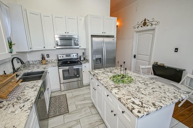 326 N Tonti St, New Orleans, LA 70119 - kitchen featuring stainless steel appliances, light stone counters, a center island, white cabinets, and a high ceiling
