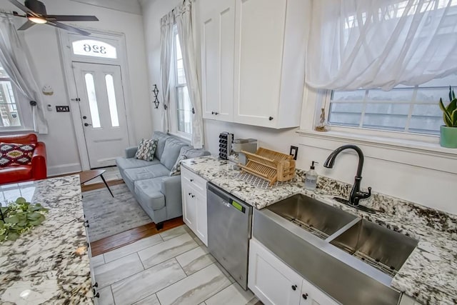 326 N Tonti St, New Orleans, LA 70119 - kitchen with stainless steel dishwasher, white cabinetry, light stone countertops, ceiling fan, and light marble finish flooring