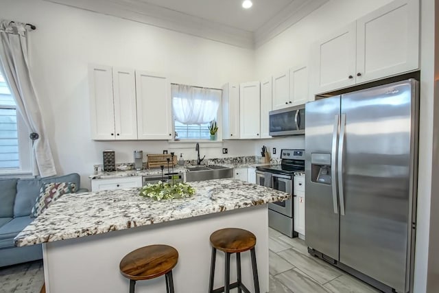 326 N Tonti St, New Orleans, LA 70119 - kitchen with appliances with stainless steel finishes, a kitchen bar, light stone counters, white cabinets, and crown molding