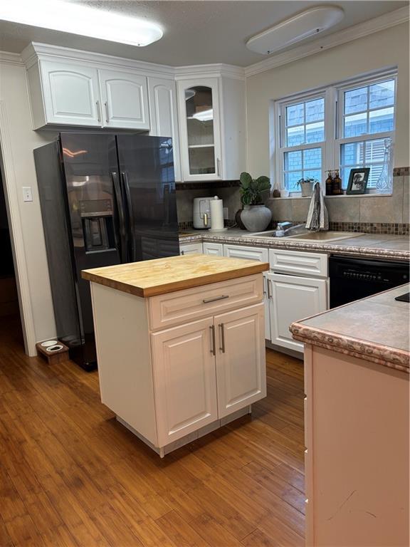 372931 Lilac Ln, Metairie, LA 70001 - kitchen with glass insert cabinets, wooden counters, white cabinetry, black appliances, and wood finished floors