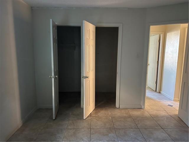 unfurnished bedroom with light tile patterned floors, a closet, and baseboards