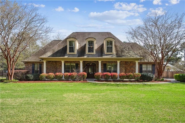 view of front of house featuring brick siding, a front yard, and fence