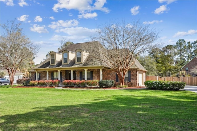 new england style home featuring brick siding, a front yard, an attached garage, and fence